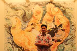 Dissa Makalingga in front of his great grandfather's mural in the Imin Center. Affandi depicted Semar and Gandhi in the palm of the hand.